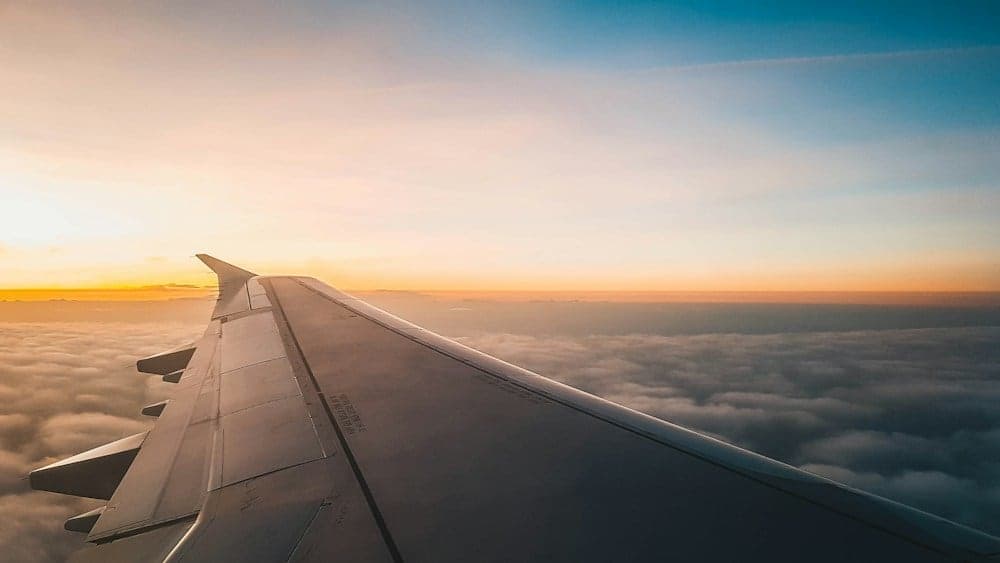 An airplane wing above the clouds at sunrise